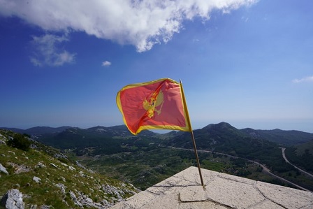 Montenegro flag raised, with beautiful mountains and hills visible behind.